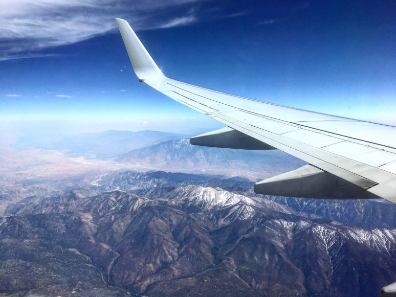 wing of airplane flying above mountains