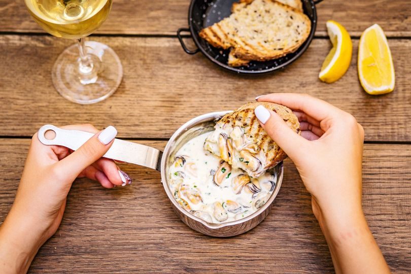 Woman eating delicious seafood with bread