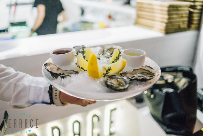 Waiter holding a plate of oysters with lemon