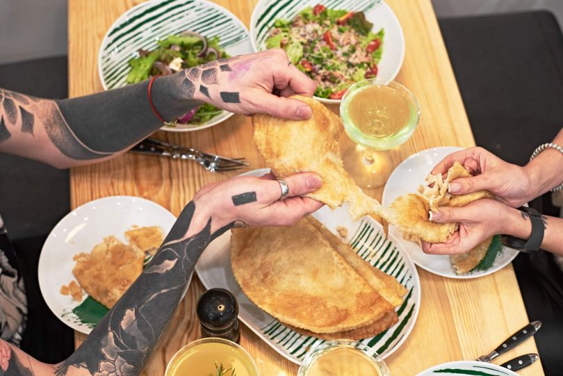 hands of two people over table with dishes and drinks