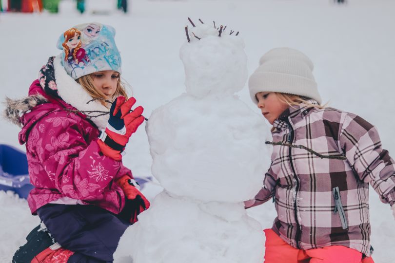 two girls making snowman
