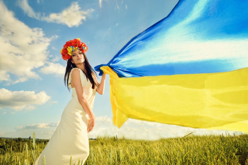 girl in field holding ukrainian flag
