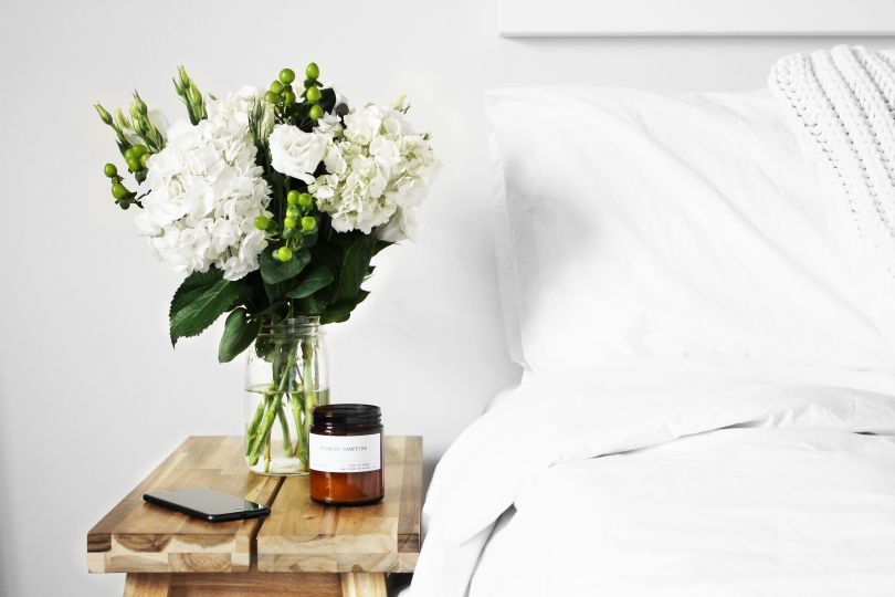 Vase with flowers near the bed