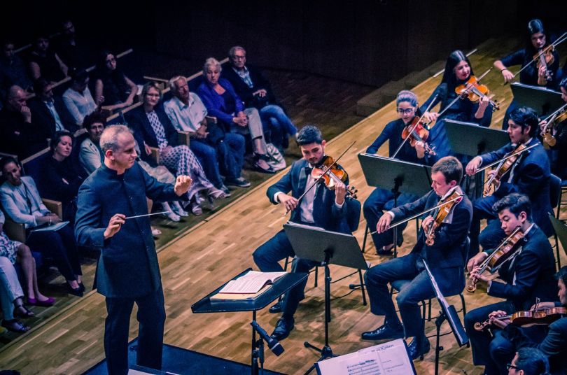 people watching orchestra playing in concert hall