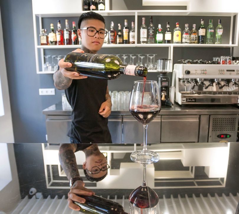 bartender puring wine into glass on bar counter