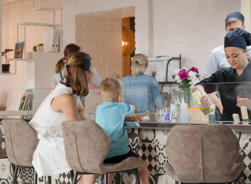 mother and son sitting at restaurant table while chef is working