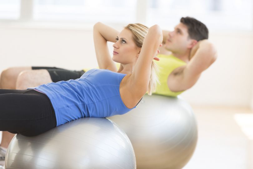 man and woman exercising on fitball