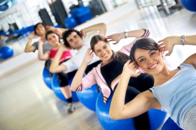 group of people smiling at pilates session with fitballs