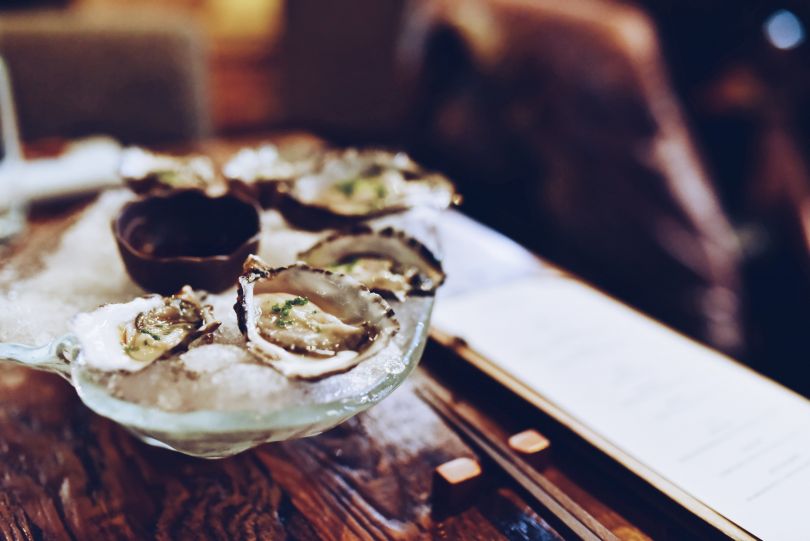 oysters in ice on glass plate on wooden table