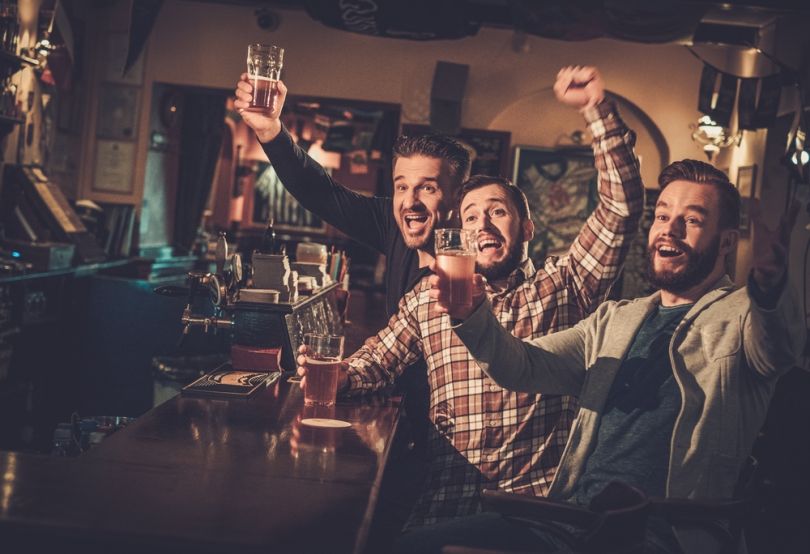 Friends cheering while watching football match in a pub